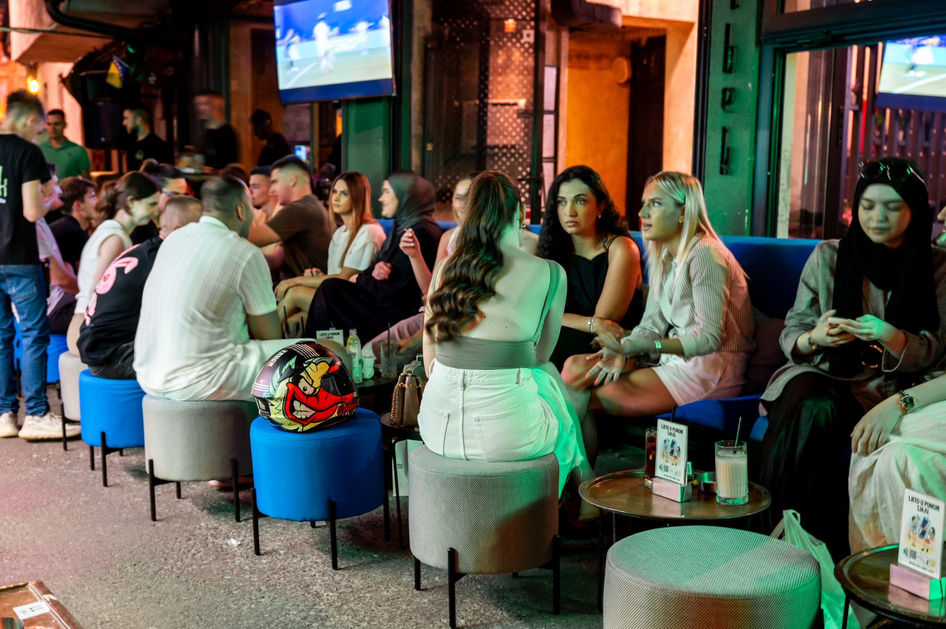 Friends gathered on the blue ottomans at night