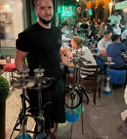 Waiter serving fresh hookahs in the garden